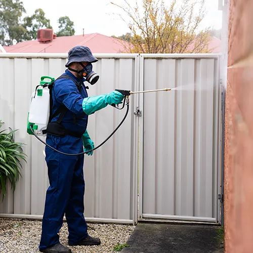 Pest control technician treating the outer perimeter of a home - Keep pests away from your home with Florida Pest Control