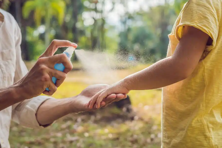 A person spraying their child with insect repellant outdoors - Keep mosquitoes away from your home with Florida Pest Control in Gainesville FL