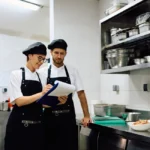 Restaurant cooks cooperating while goin through check list in the kitchen