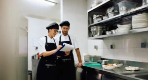 Restaurant cooks cooperating while goin through check list in the kitchen