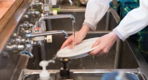 Young lady is woking at kitchen cleaning dishes