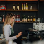 Young barista woman skillfully preparing coffee with a professional machine in a bustling cafe, radiating joy and expertise