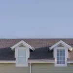 Square frame Two small dormer windows in the roof of an urban house flanked by leafy green trees