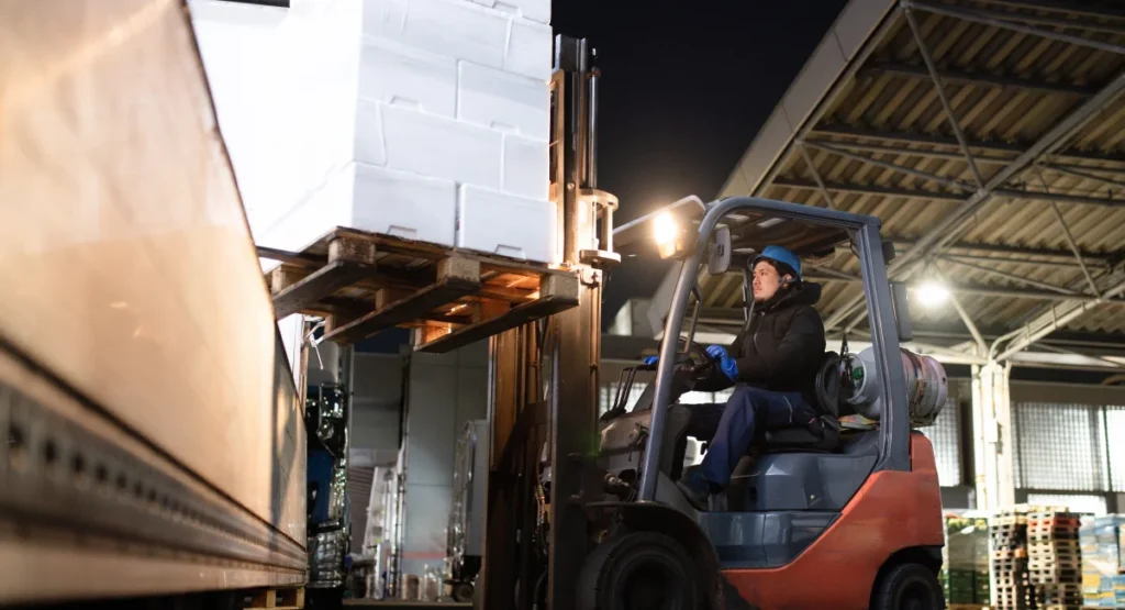 a man driving a forklift loaded with cargo