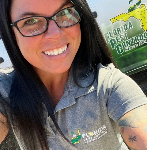 Charlee a florida pest technician showing off her branded tshirt in front of florida pest truck