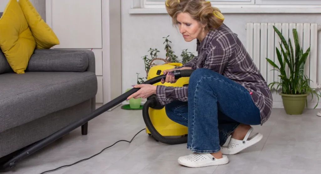 Woman vacuuming cockroaches under a sofa