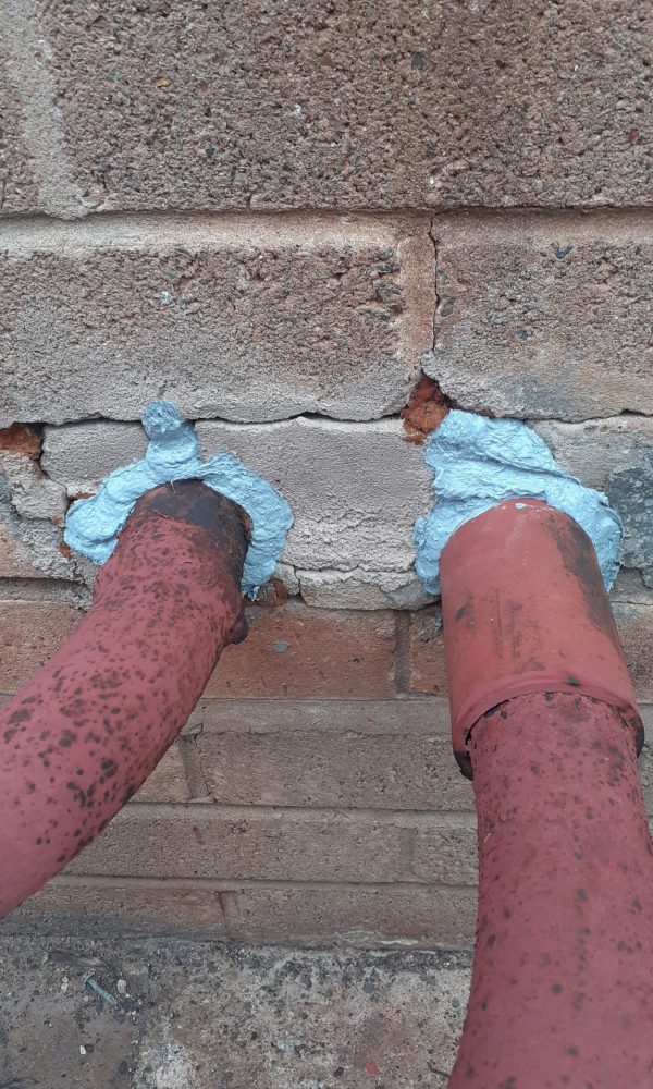 Two pipes surrounded by sealant where they enter a building to stop Australian cockroaches from entering