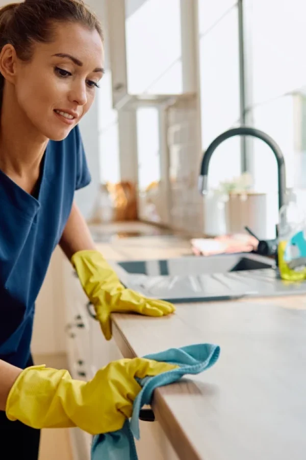 Woman cleaning countertops to eliminate residue and crumbs that may attract cockroaches